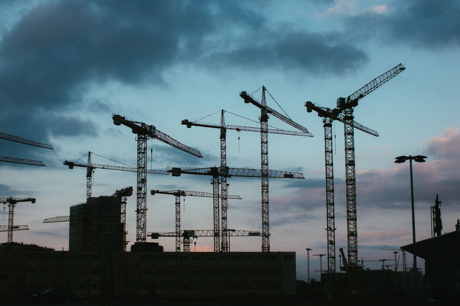 Tower crane silhouettes against a dusk sky
